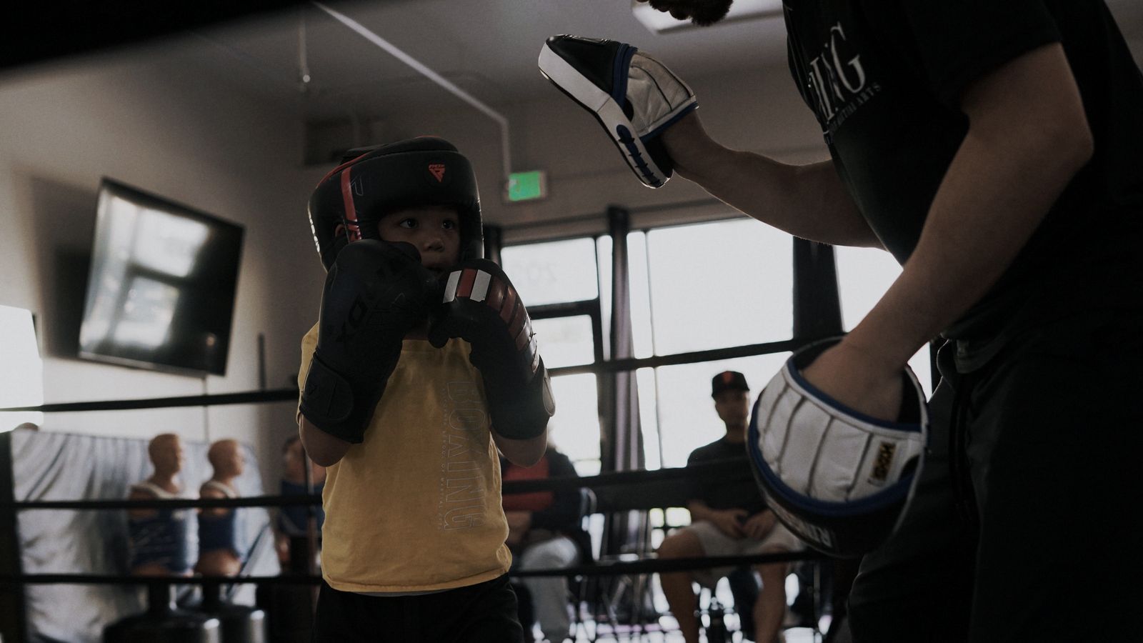 A young boxer working the coach’s mitts